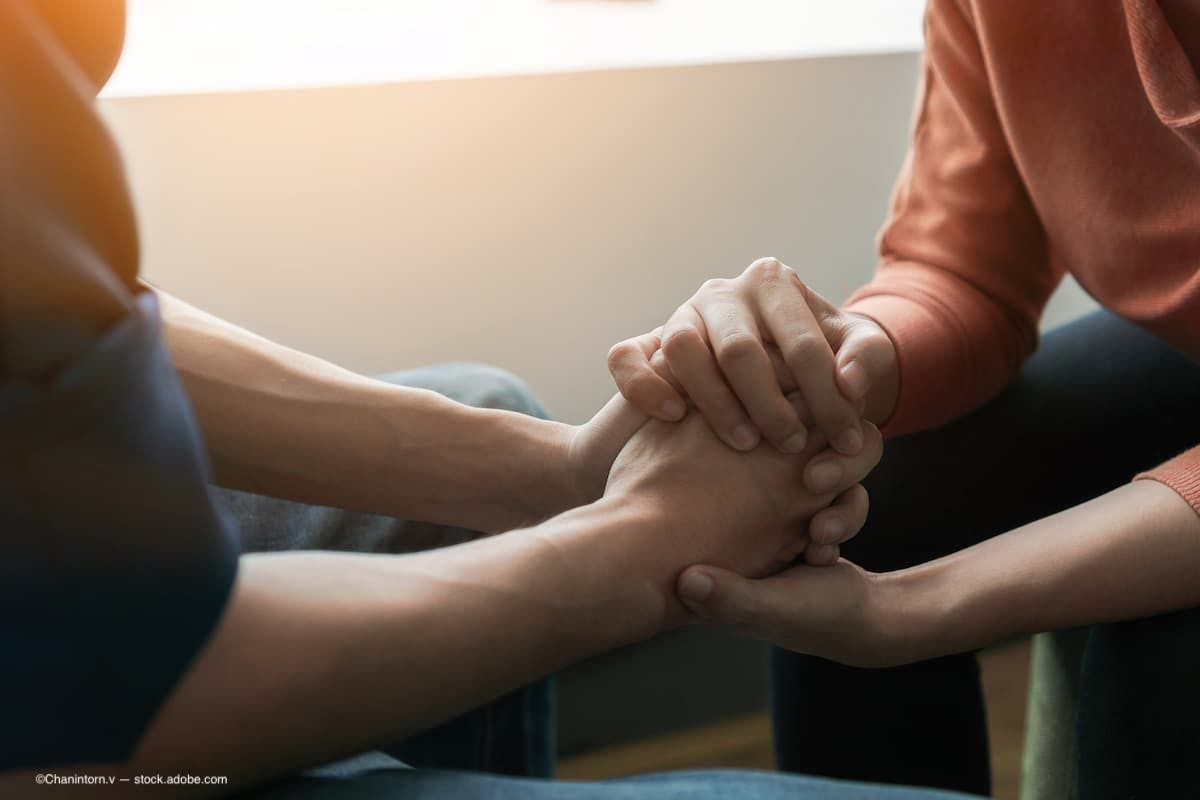 An image of two men holding hands to support and comfort one another (Image Credit: AdobeStock/Chanintorn.v)