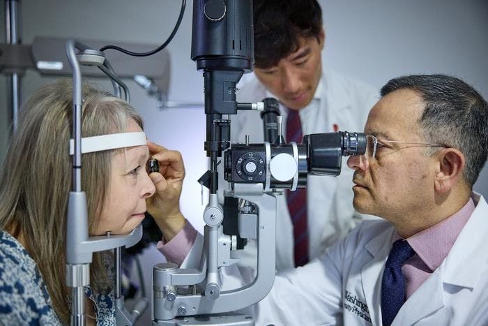 Ophthalmologist Rajendra S. Apte, MD, PhD, (right), of Washington University School of Medicine in St. Louis, examines patient Patricia Collins (left) while medical student Wilson Wang observes. Collins is a participant in a clinical trial that tests the safety and efficacy of an FDA-approved drug in stabilizing vision in patients with RVCL-S, a rare genetic disease that affects tiny blood vessels in the body. (Image credit: Matt Miller)