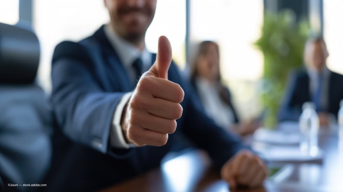 (Image Credit: AdobeStock/Jouni) man in a board room with a thumbs up 